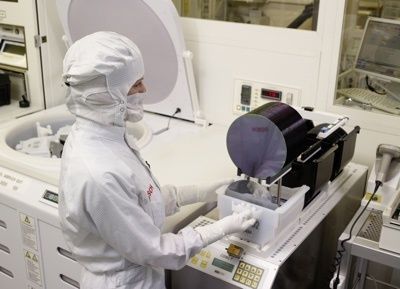 Opérateur en combinaison manipulant une plaquette de silicium en salle blanche