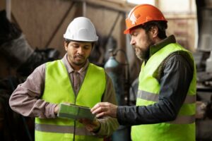 Deux ouvriers en gilet haute visibilité examinent une tablette sur un chantier